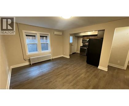 A spacious room with wood flooring and a window with a white frame.