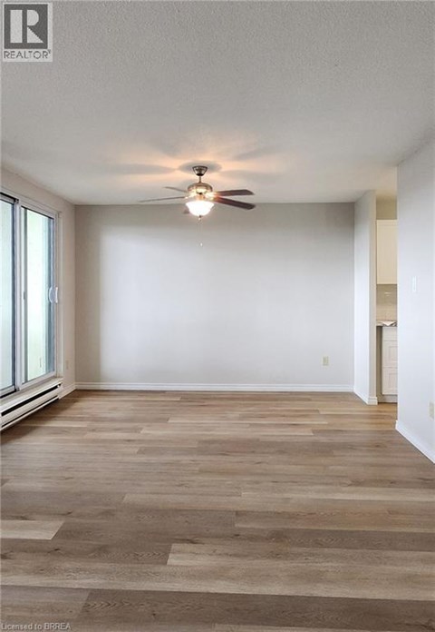 A room with a ceiling fan and wooden flooring.