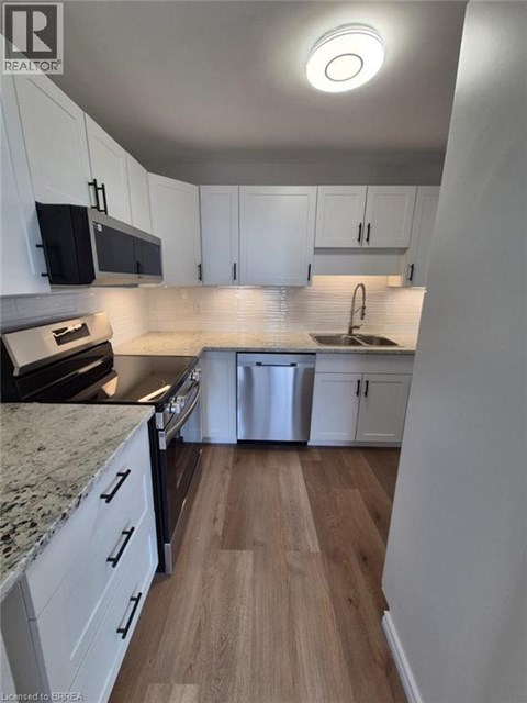 A kitchen with white cabinets and a wooden floor.