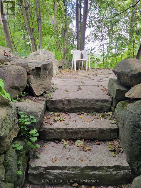 A white chair is placed on a stone staircase in a forest.