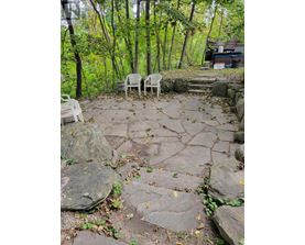 Two white chairs are placed on a stone patio.