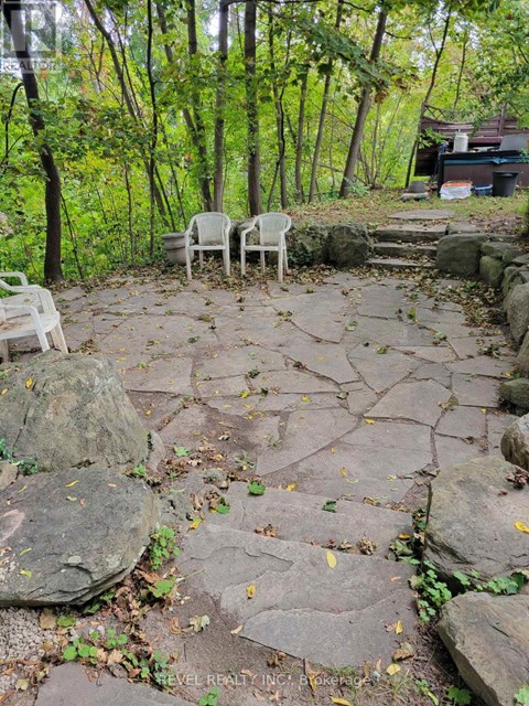 Two white chairs are placed on a stone patio.