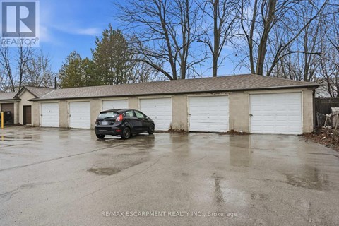 A black car is parked in front of a building with a sign that reads RE/MAX ESCARPMENT REALTY INC. Brokerage.