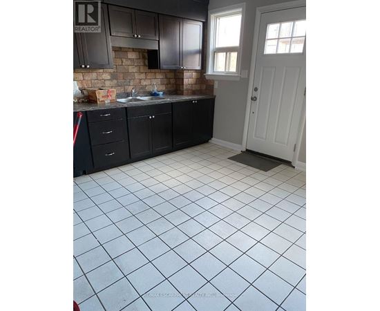 A kitchen with black cabinets and a white door.