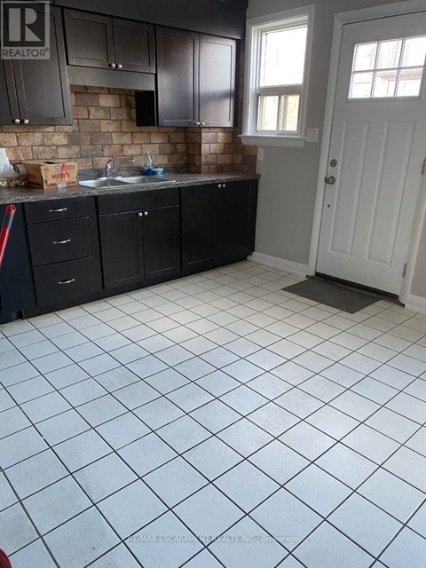 A kitchen with black cabinets and a white door.