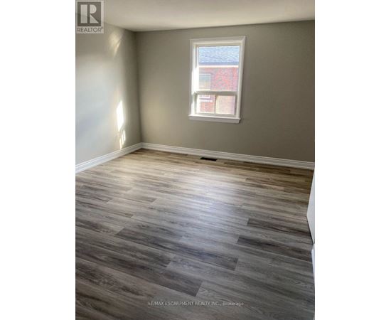 A room with a window and wooden flooring.