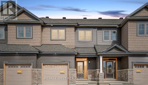 A row of houses with the sign RE/MAX West Realty Inc. Brokerage in front.