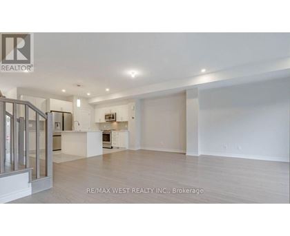 A spacious, empty room with a kitchen area in the background.