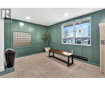 A room with a bench, a plant, and a calendar on the wall.