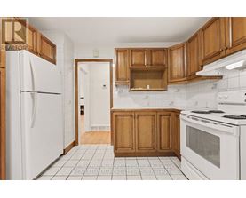 A kitchen with white appliances and wooden cabinets.