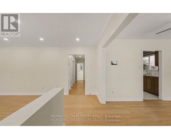 A spacious room with wooden floors and white walls, part of a real estate brokerage.