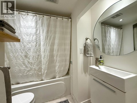 A white bathroom with a shower curtain and a round mirror.
