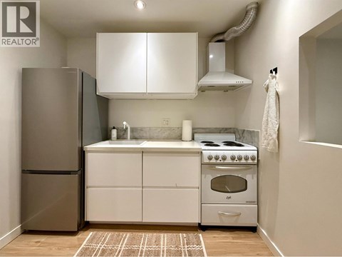 A kitchen with white cabinets and a stainless steel refrigerator.