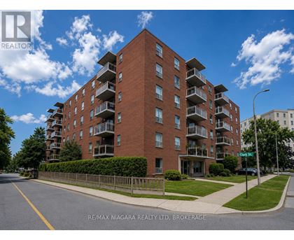 A large red brick apartment building with balconies on the upper floors.