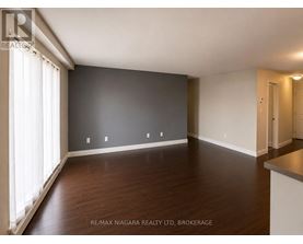 A spacious room with wooden floors and white walls.