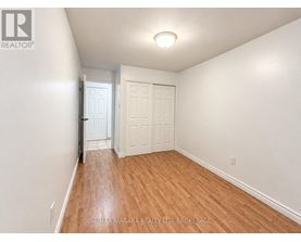 A room with wooden flooring and a window with blinds.