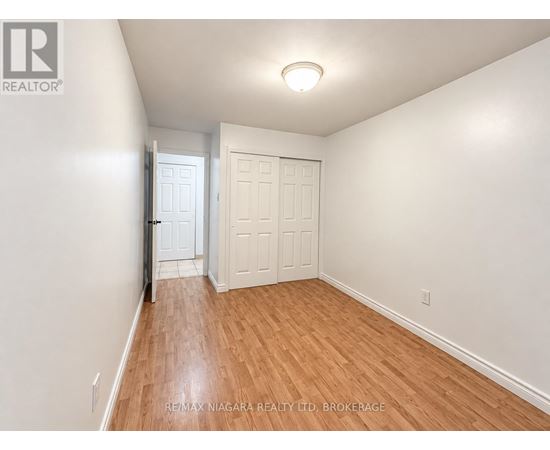 A room with wooden flooring and a window with blinds.