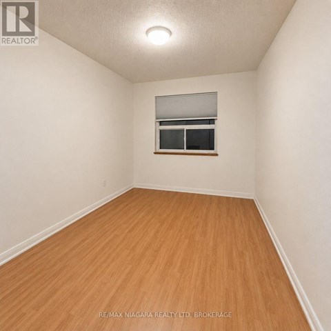 A room with wooden flooring and a window with blinds.