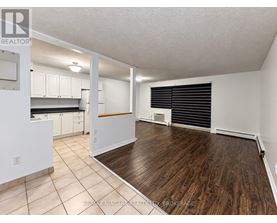 A spacious room with a kitchen area and a dining table.
