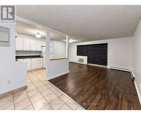 A spacious room with a kitchen area and a dining table.