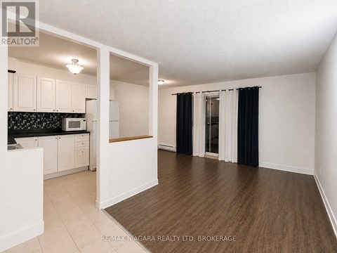 A spacious room with a kitchen area and a dining table.