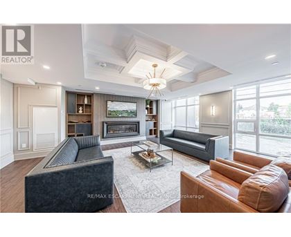 A living room with a grey couch, a brown leather couch, a coffee table and a fireplace.