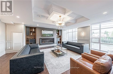 A living room with a grey couch, a brown leather couch, a coffee table and a fireplace.