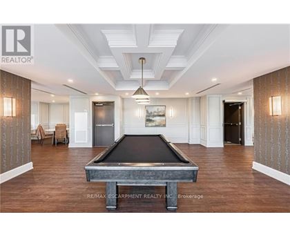 A pool table is in the middle of a room with wood floors and a high ceiling.