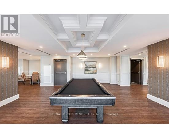 A pool table is in the middle of a room with wood floors and a high ceiling.