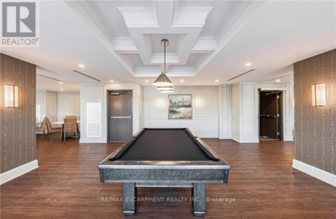 A pool table is in the middle of a room with wood floors and a high ceiling.