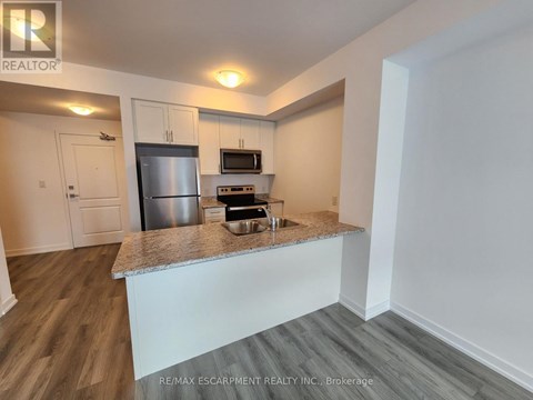 A kitchen with a stainless steel refrigerator, microwave, and oven.