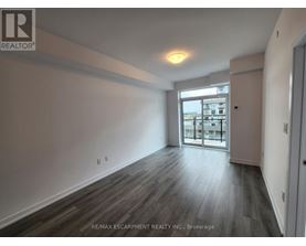 A spacious room with wooden flooring and a large window.