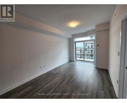 A spacious room with wooden flooring and a large window.