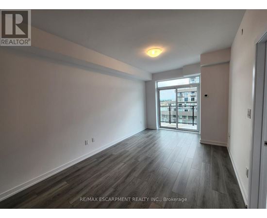 A spacious room with wooden flooring and a large window.