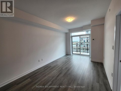 A spacious room with wooden flooring and a large window.