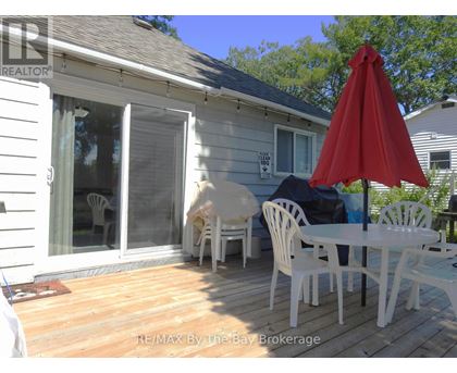 A white patio with a red umbrella and chairs.