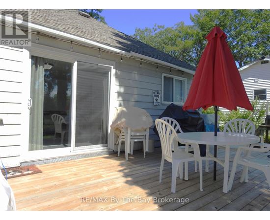 A white patio with a red umbrella and chairs.
