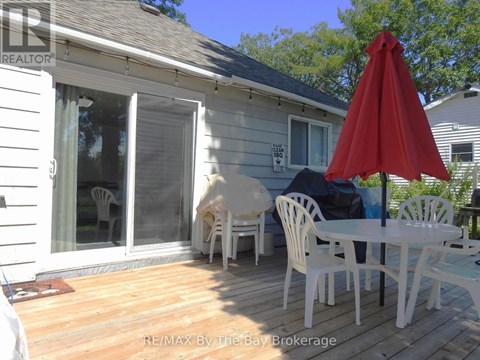 A white patio with a red umbrella and chairs.