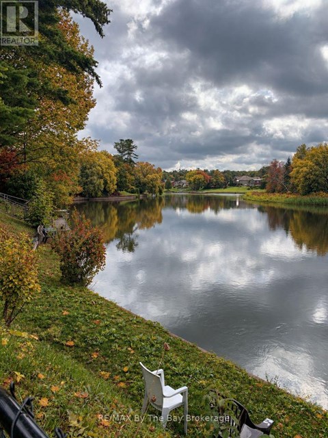 A serene lake surrounded by autumn trees and a cloudy sky.