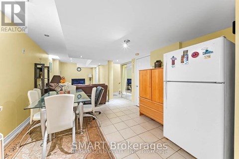 A kitchen with a white fridge and a dining table with chairs.
