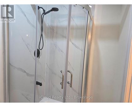 A glass shower door with a handle and a hose attached to it.