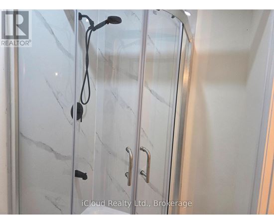 A glass shower door with a handle and a hose attached to it.