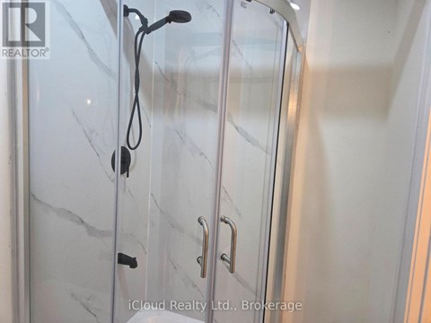 A glass shower door with a handle and a hose attached to it.