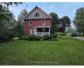A red brick house with a white porch and a green lawn.
