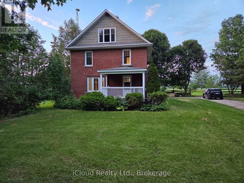 A red brick house with a white porch and a green lawn.