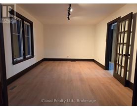 A room with wooden flooring and a ceiling light fixture.