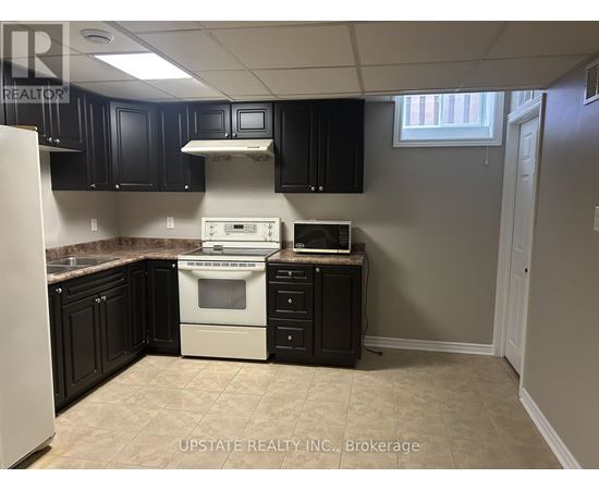 A kitchen with black cabinets and a white stove top oven.