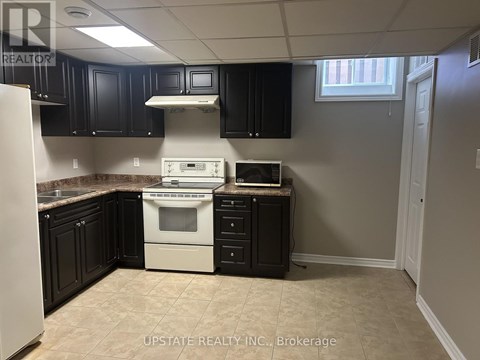 A kitchen with black cabinets and a white stove top oven.