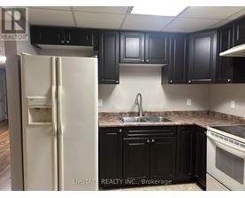 A kitchen with a white refrigerator and black cabinets.