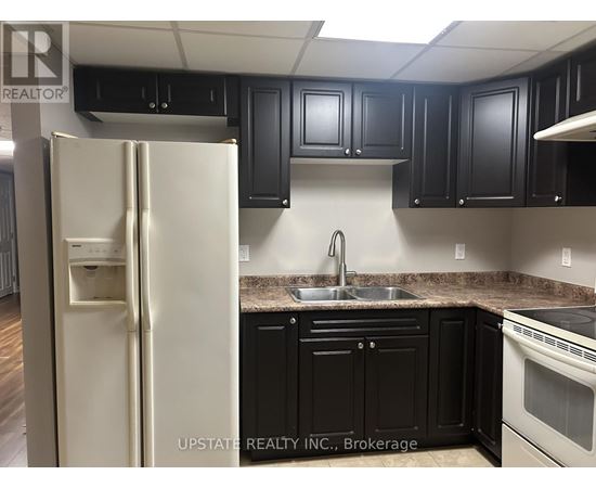 A kitchen with a white refrigerator and black cabinets.